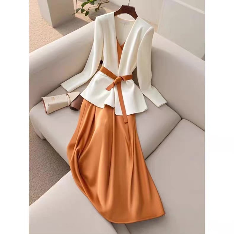 Traditional outfit with white top and orange skirt on a hanger against a neutral background