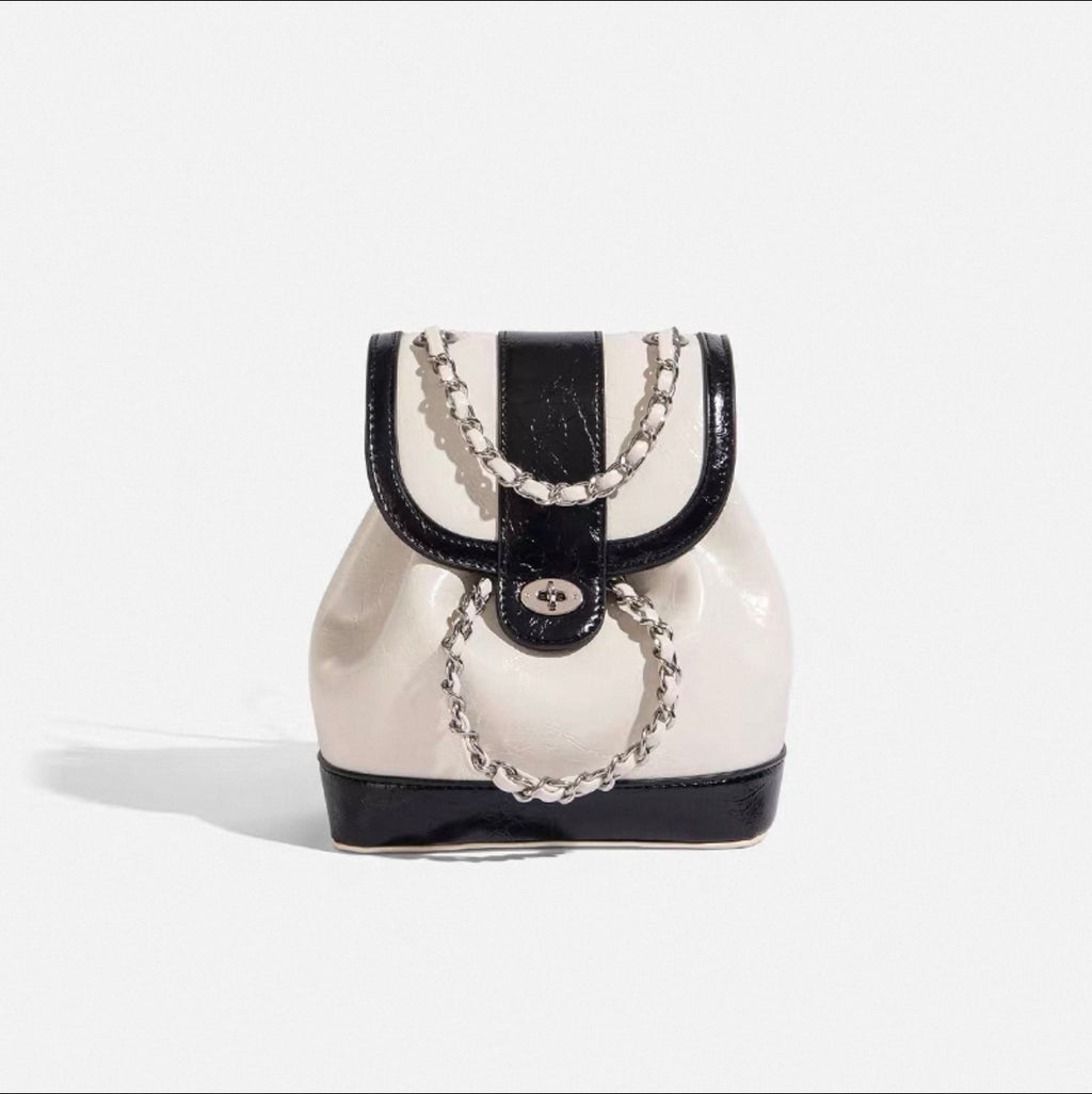 Black and white handbag with chain detail on a light gray background