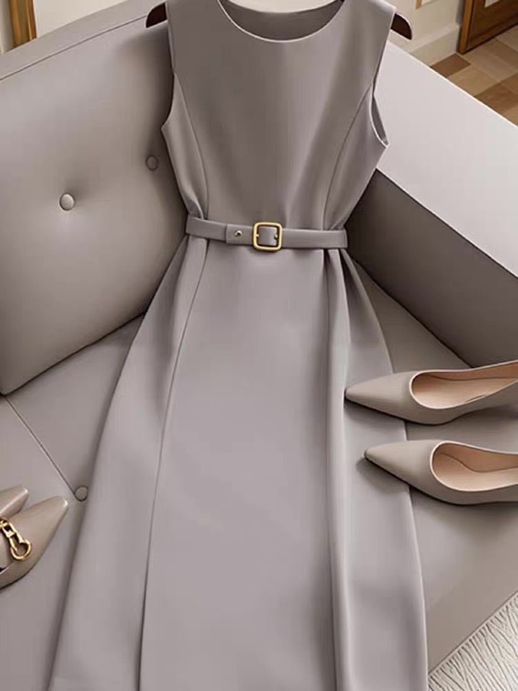 Gray dress with a belt on a gray couch, accompanied by beige shoes.