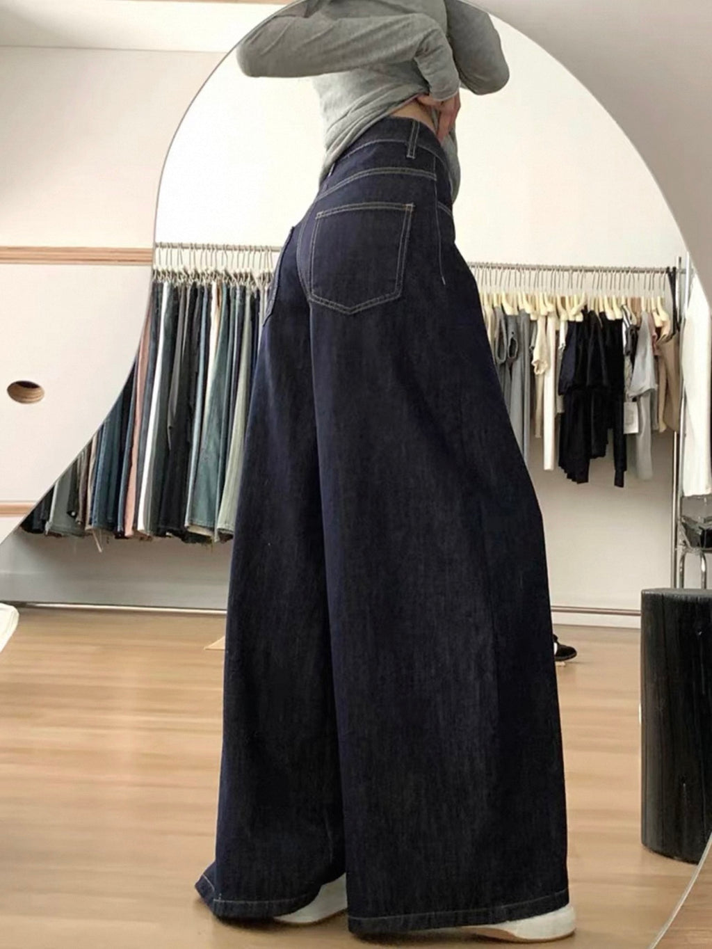 Person wearing a long black denim skirt in a clothing store.