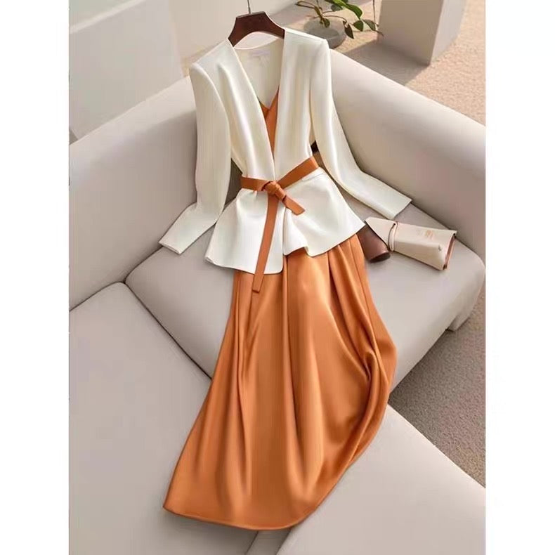 White top and orange skirt set on a hanger against a neutral background