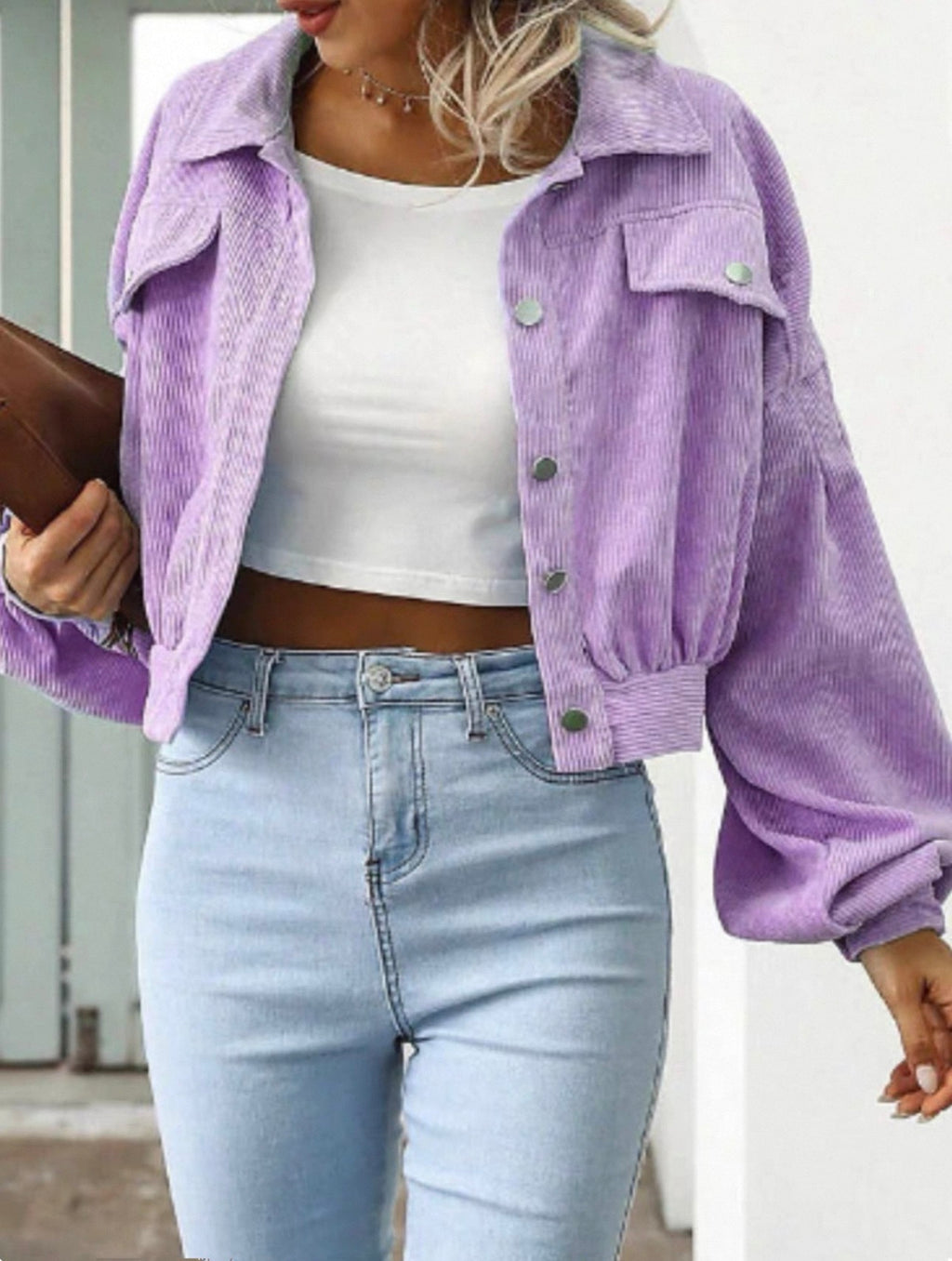 Person wearing a purple corduroy jacket over a white top and light blue jeans.
