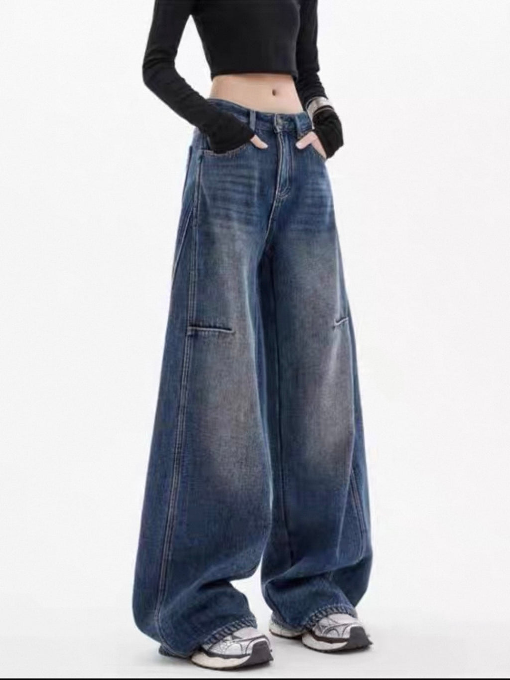 Person wearing wide-leg jeans and a black top on a white background