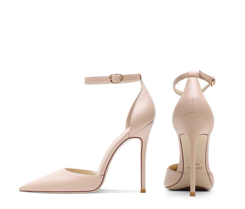 Nude leather stiletto heels with pointed toes and ankle straps, hollow sides, sleek high heel design.