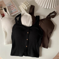 Three ribbed knit tops in black, white, and brown on a light surface.