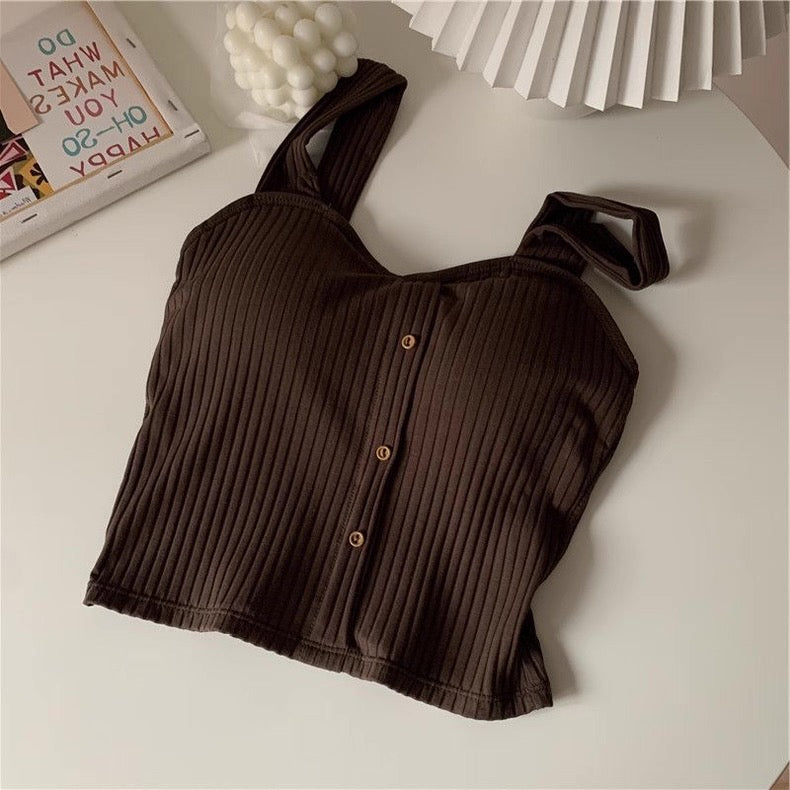 Brown ribbed crop top on a light surface with decorative items in the background