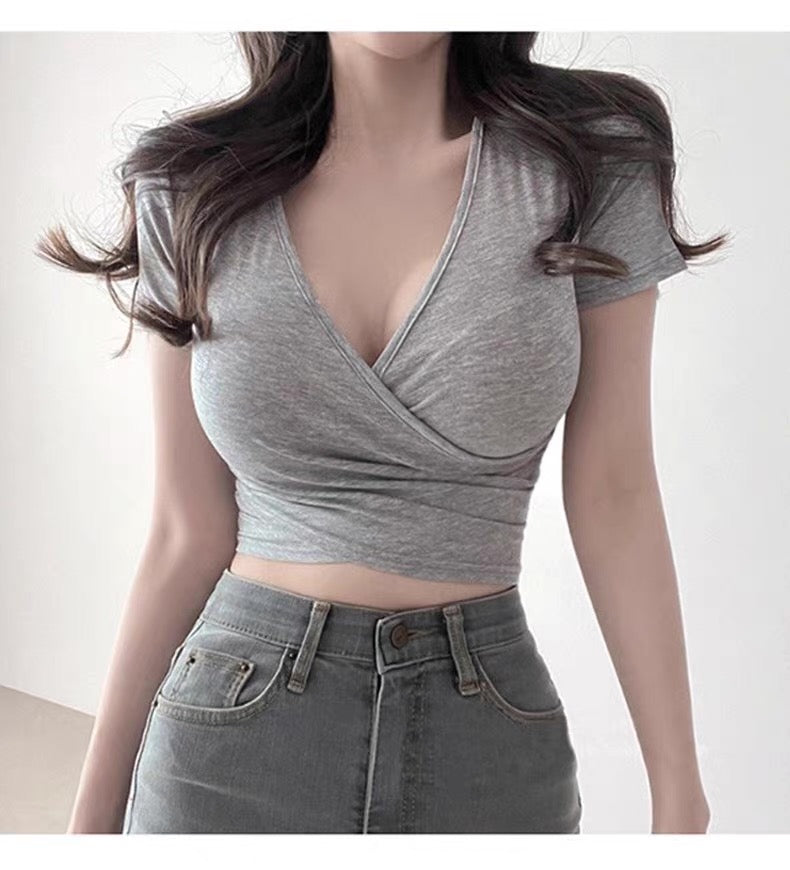 Person wearing a gray crop top and jeans on a plain background