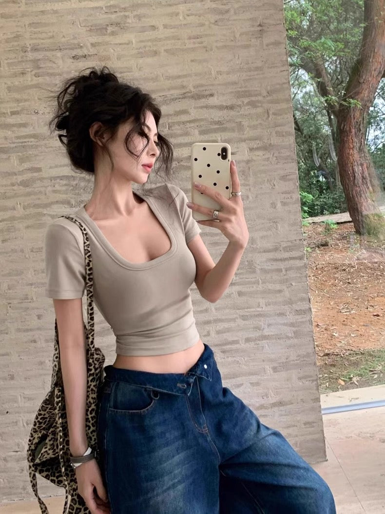 Woman taking a mirror selfie wearing a beige top and blue jeans, with a leopard print bag.