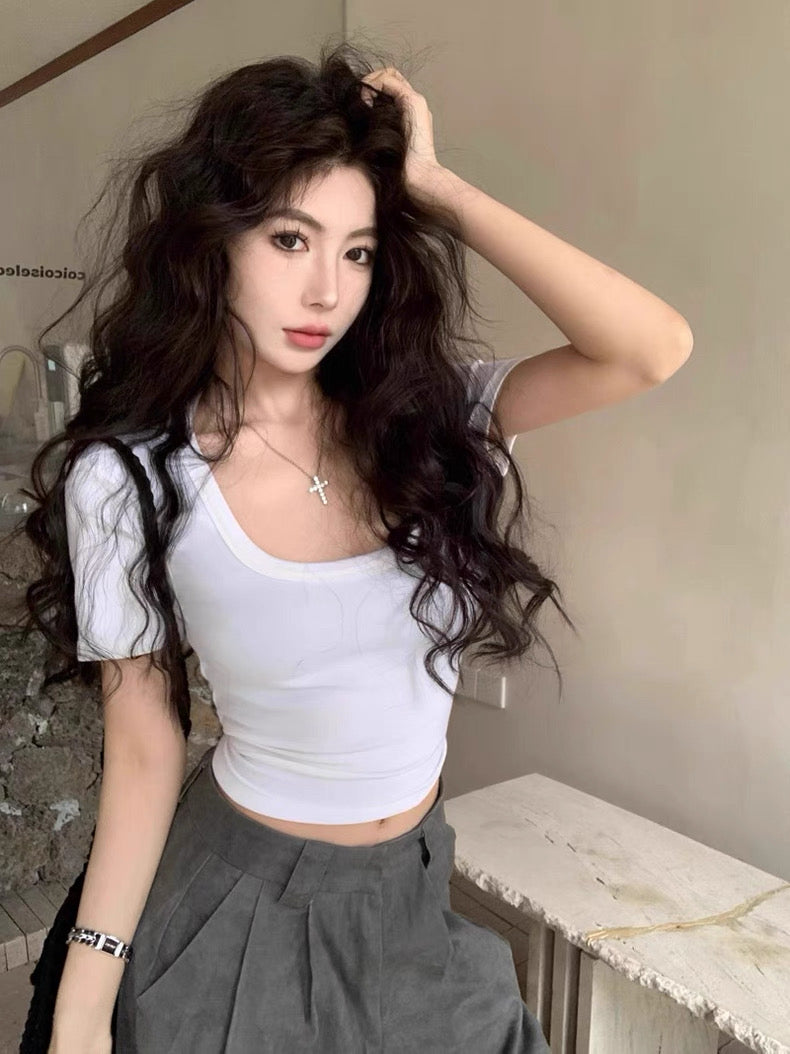 Woman with white crop top styled hair posing indoors