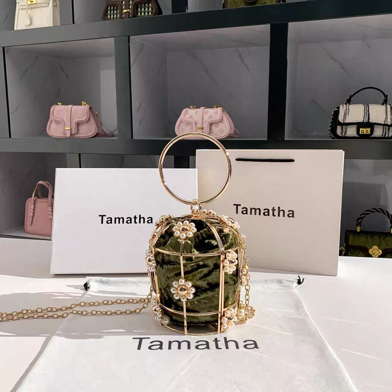 Green handbag with gold chain and handle on a white surface with 'Tamatha' branding.