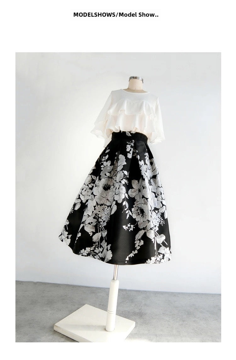 Mannequin wearing a black floral skirt and white top on a plain background