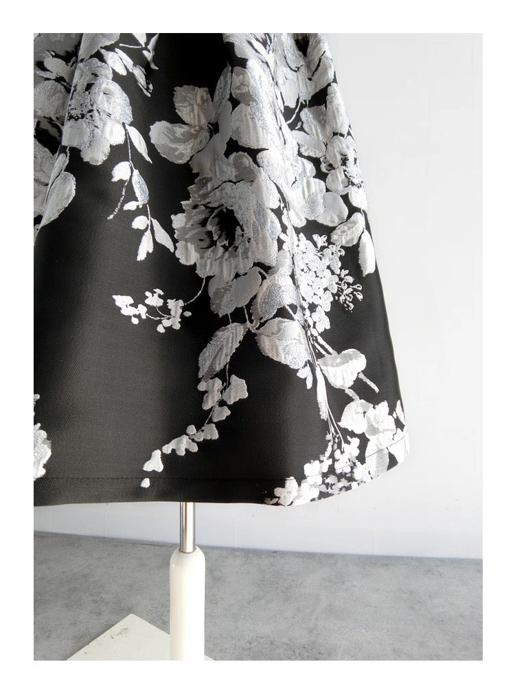 Black dress with white floral pattern on a mannequin against a white background