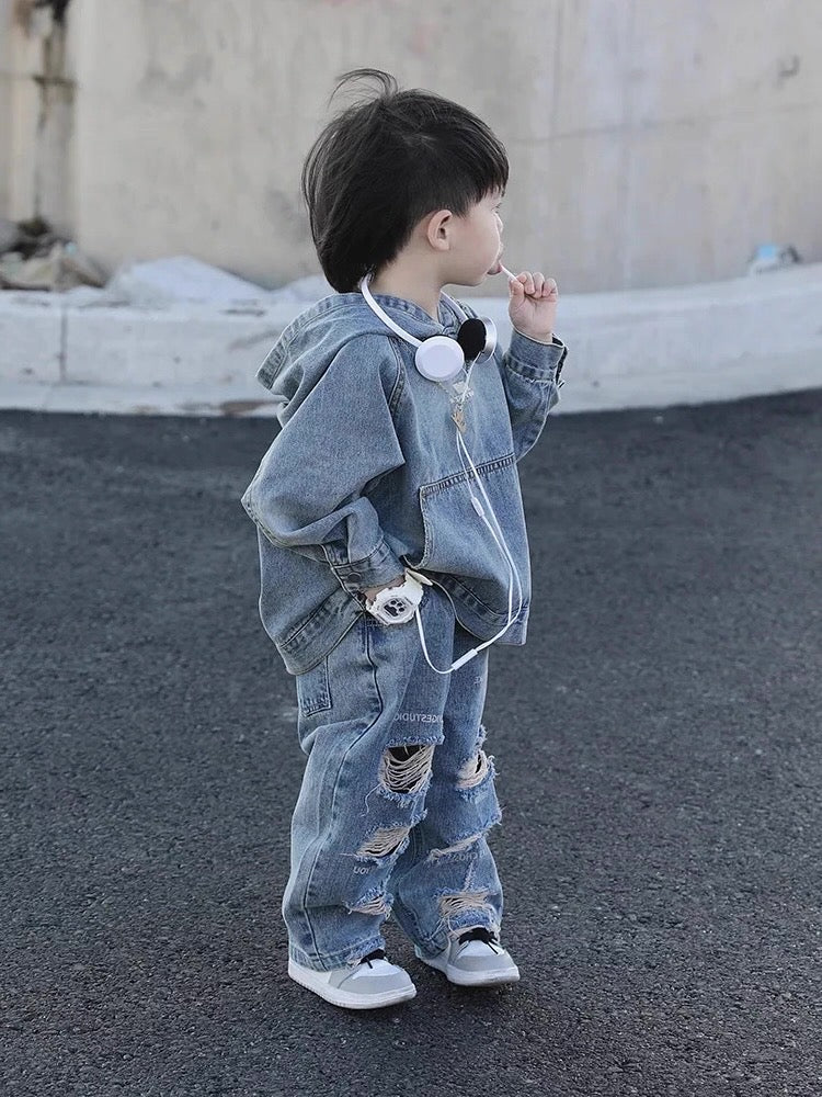 Child wearing a denim outfit with headphones, standing on a street.