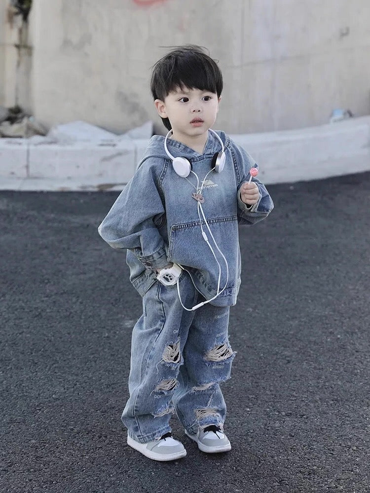 Child wearing a denim outfit with headphones, standing on a street.