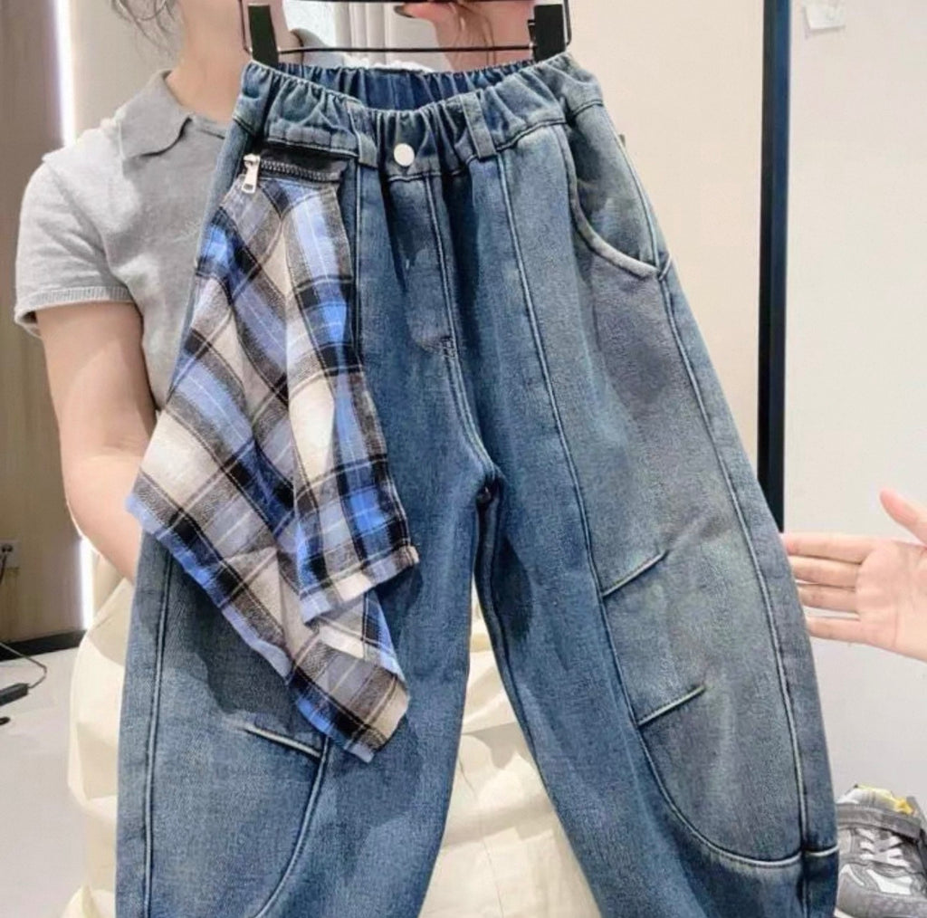 Person wearing blue jeans and a plaid shirt, standing indoors.