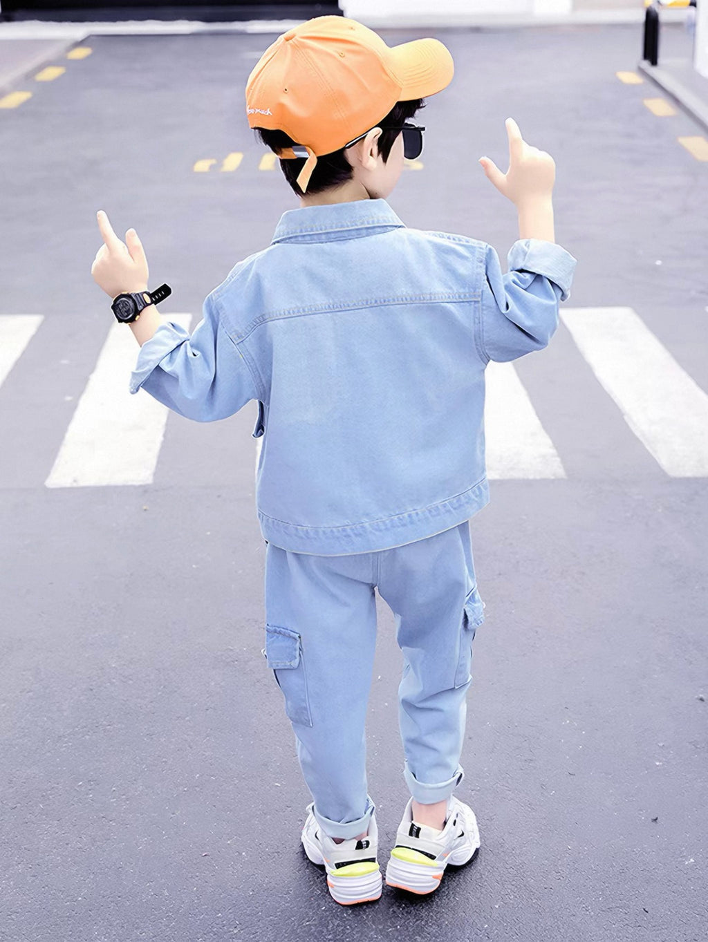 Child wearing a light blue denim outfit with a cap, standing on a crosswalk.