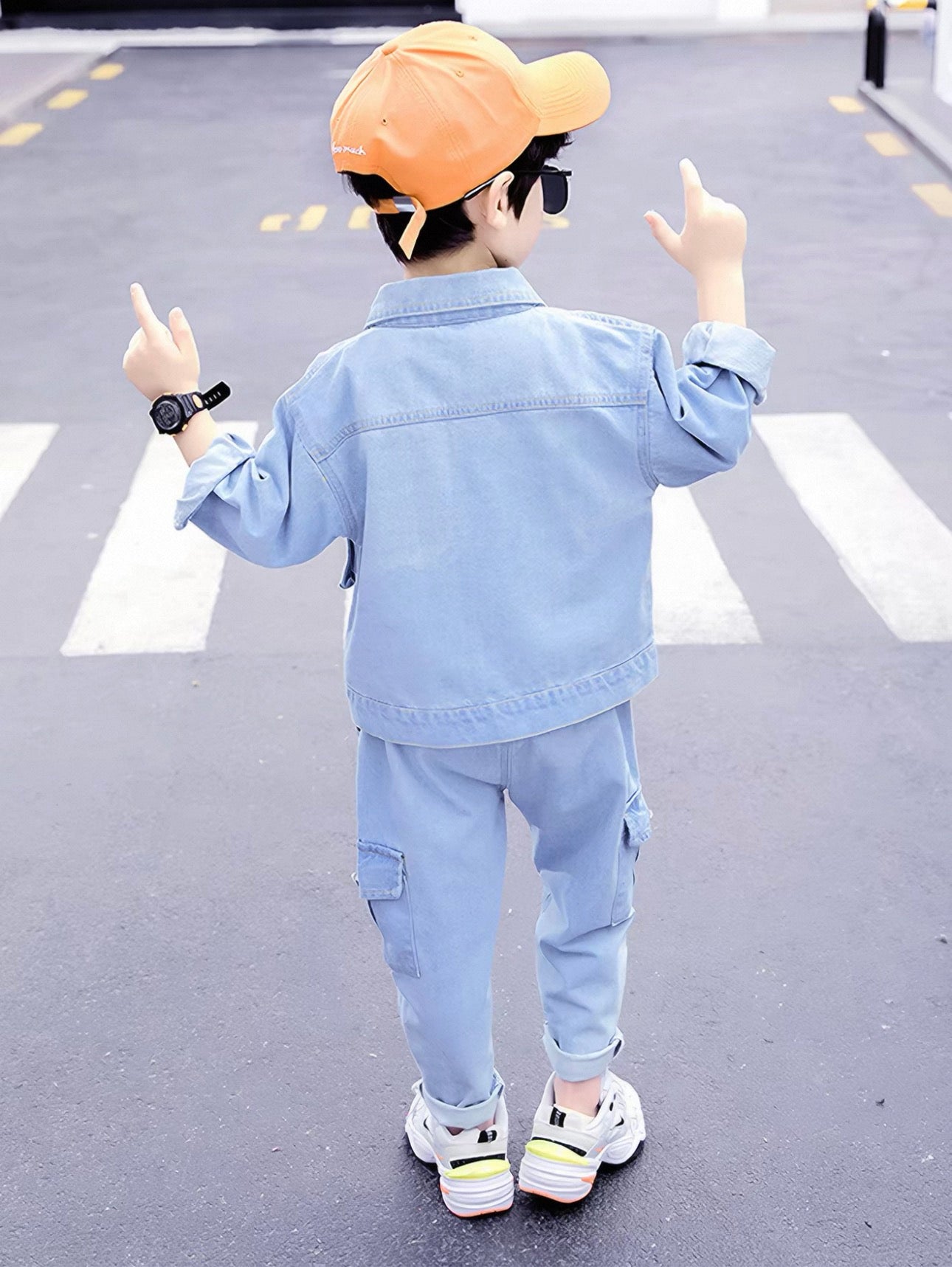 Child wearing a light blue denim outfit with a cap, standing on a crosswalk.