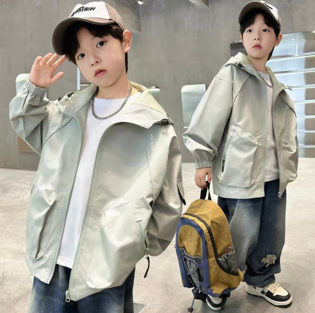 Two children wearing matching outfits with light jackets and caps in an indoor setting.