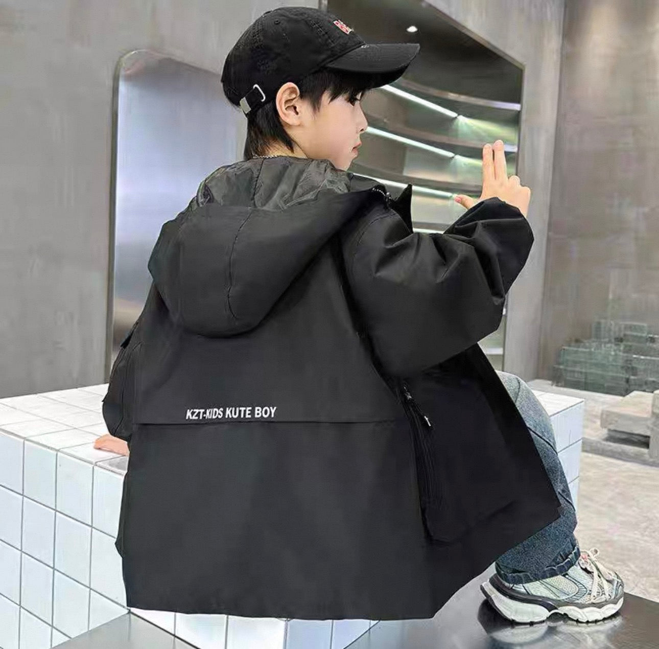 Person wearing a black jacket with text, standing in an indoor setting.