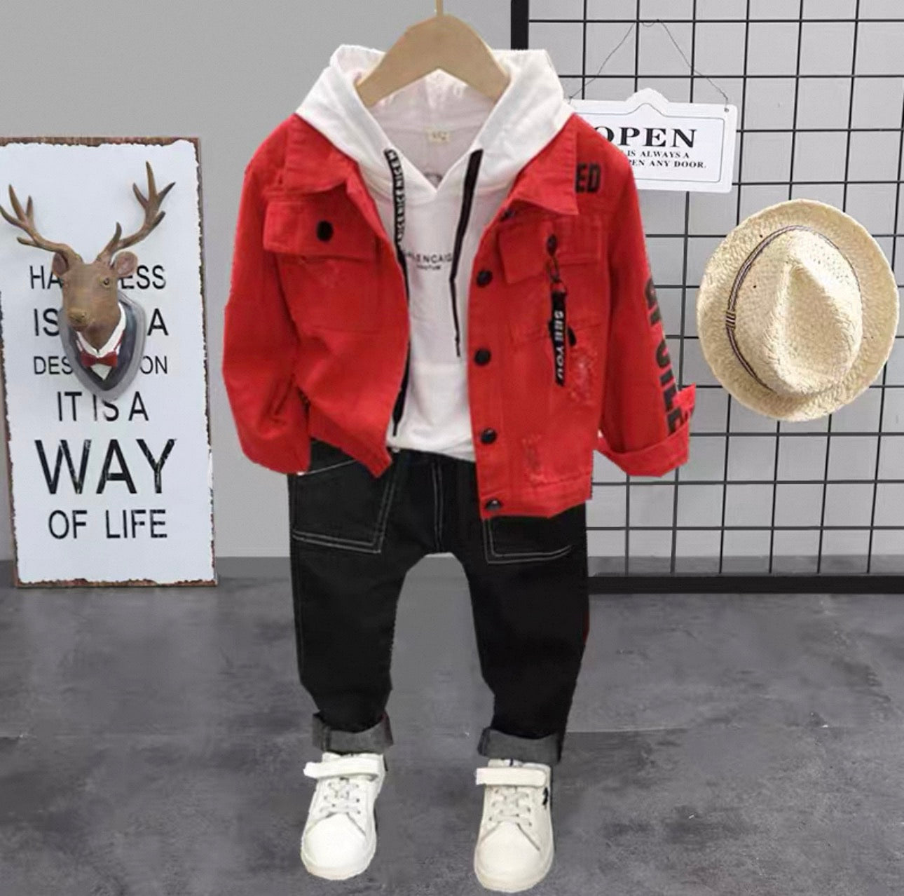 Red jacket, white hoodie, black pants, and white sneakers on a hanger with a hat and motivational sign in the background.