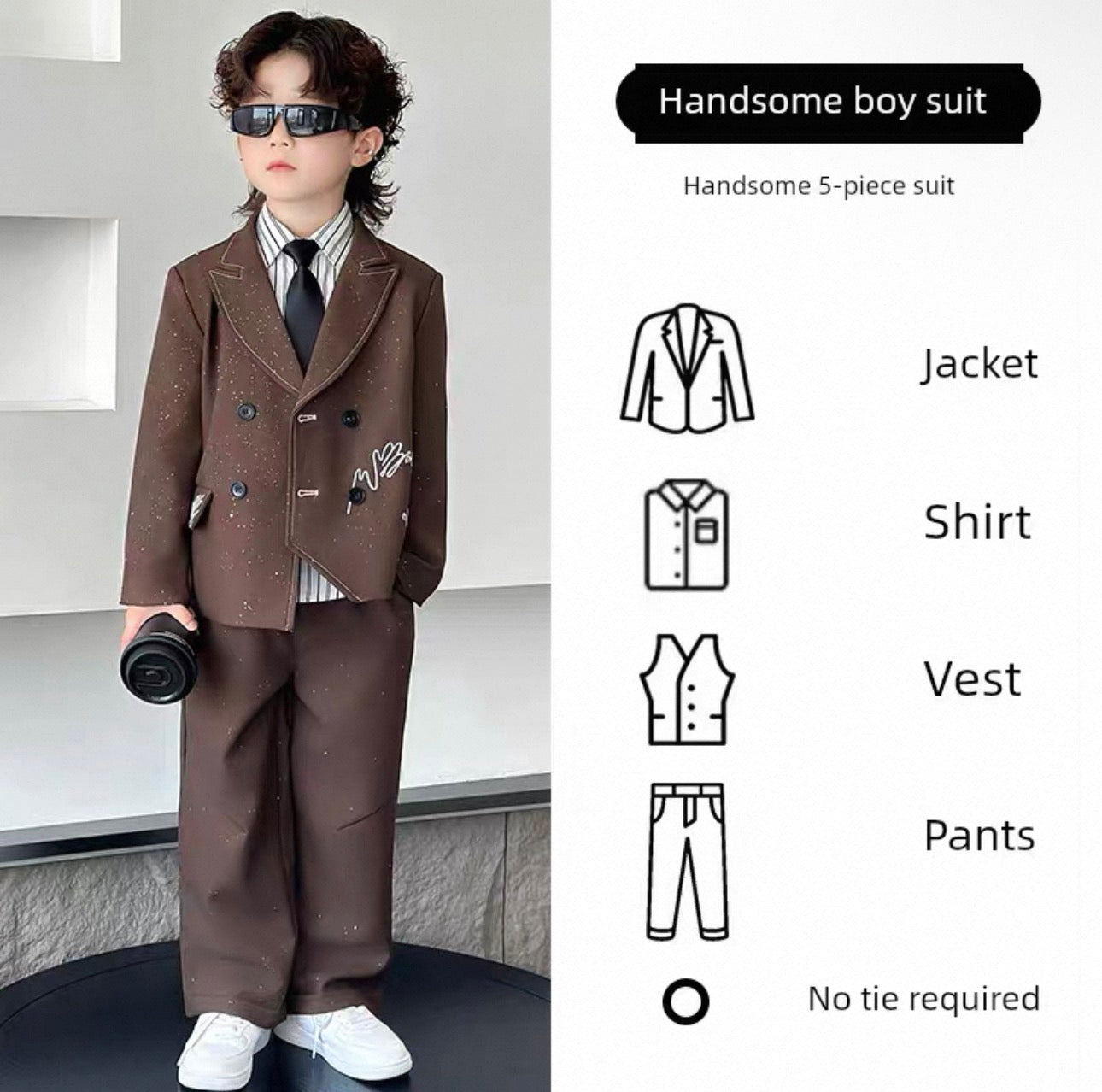 Child wearing a formal brown suit with sunglasses, standing against a light-colored wall.