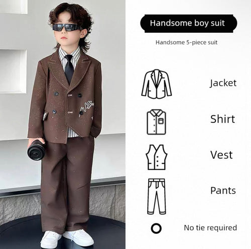 Child wearing a formal brown suit with sunglasses, standing against a light-colored wall.