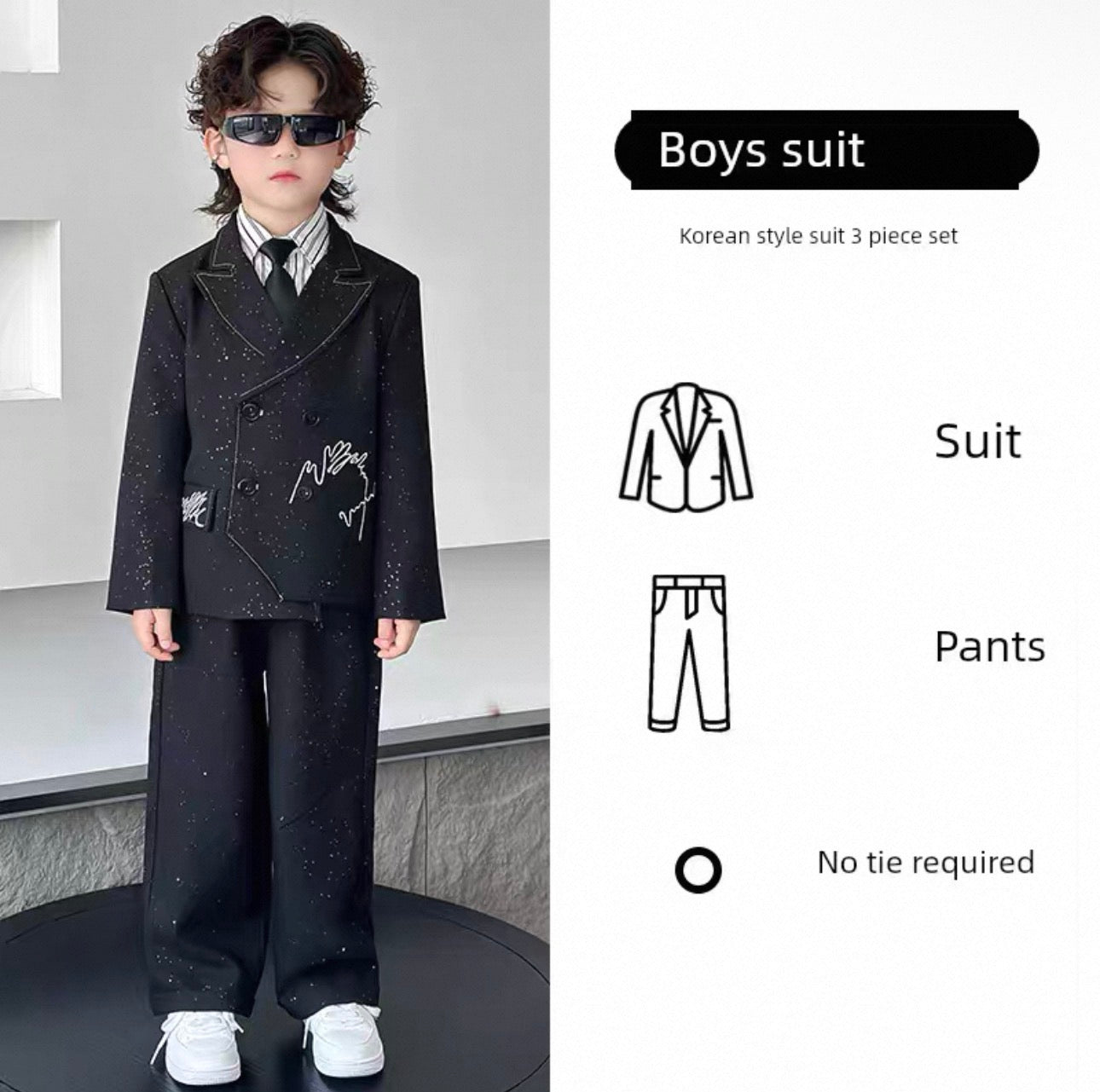 Child wearing a black suit with sunglasses, standing against a neutral background.
