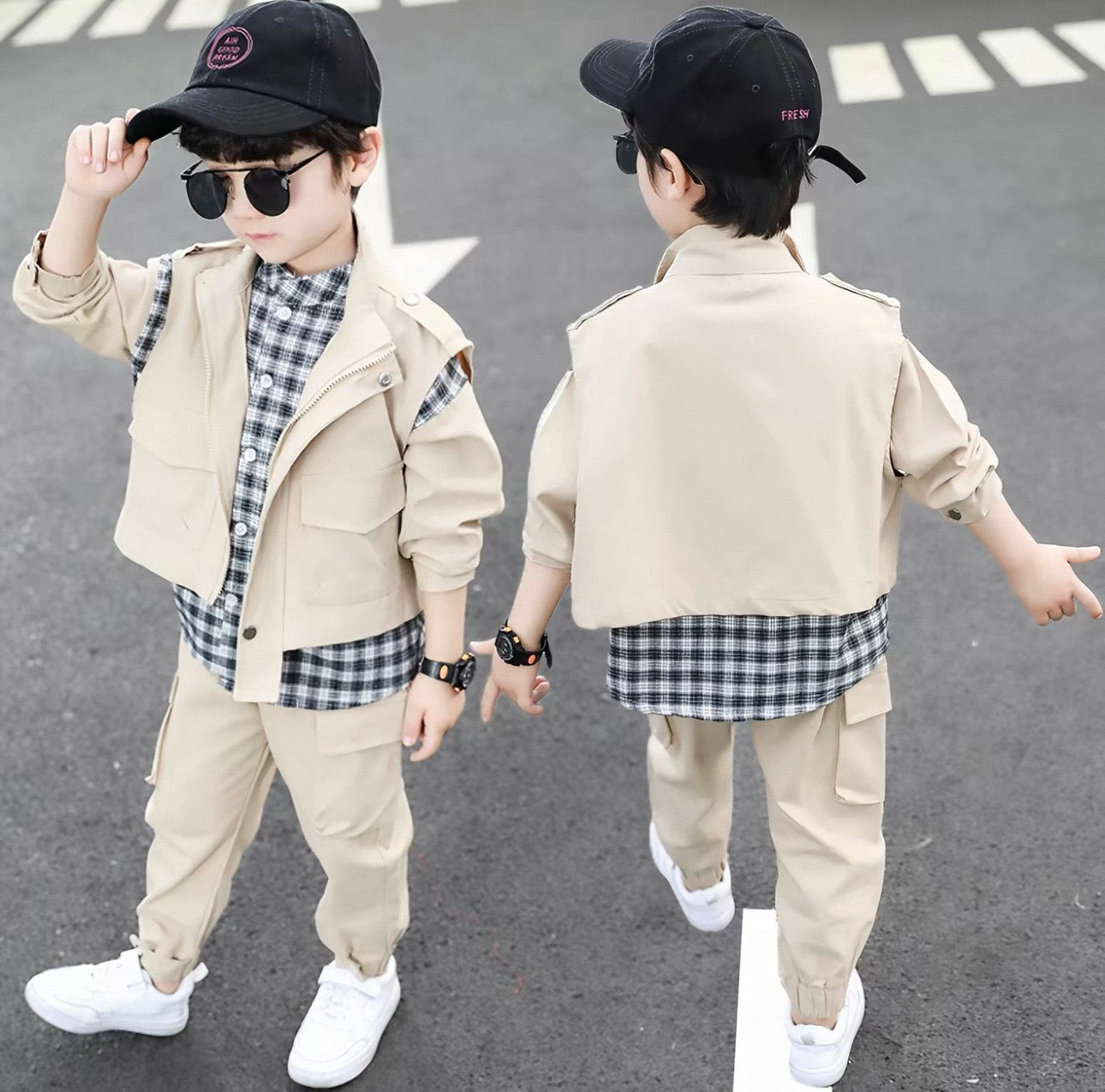 Two children wearing matching outfits of beige jackets, plaid shirts, and pants on a street.