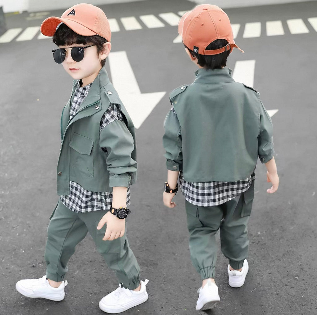 Two children in matching green outfits with plaid shirts on a road.