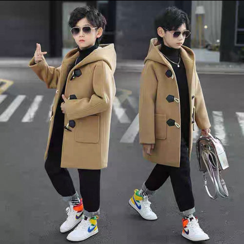 Two children wearing tan coats on a street.