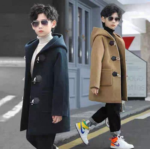 Two children wearing long coats on a street.