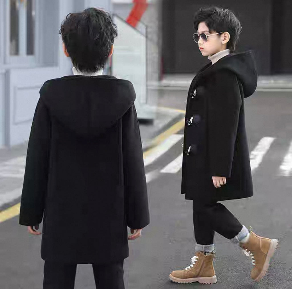Two children wearing black coats on a city street.