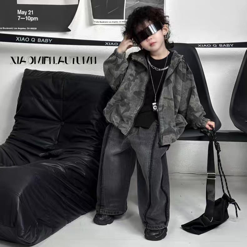 Child wearing a camouflage jacket and black pants in a room with a black bean bag chair.