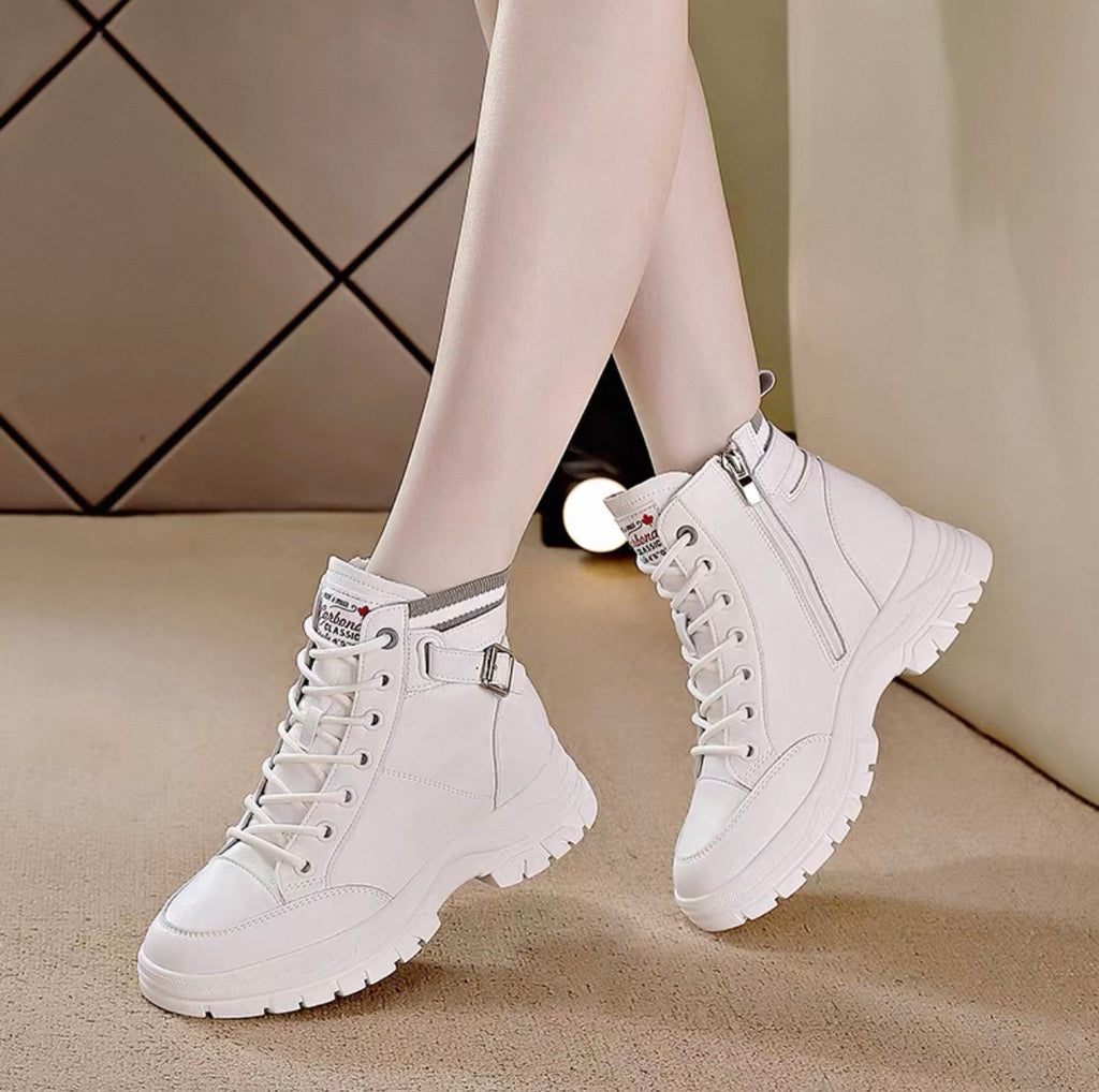 White high-top sneakers worn with light-colored tights on a neutral background