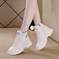 White high-top sneakers worn with light-colored tights on a neutral background