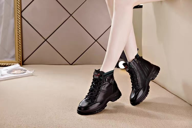 Person wearing black high-top sneakers sitting on a chair with a geometric wall design in the background.