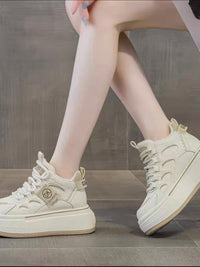 White high-top sneakers worn by a person on a wooden floor.