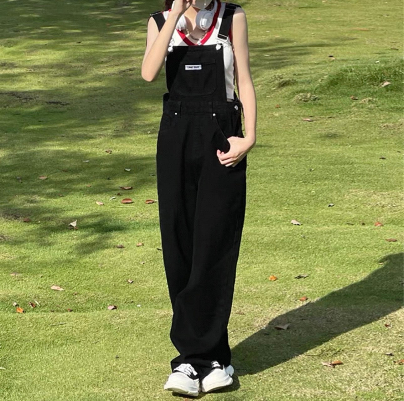 Person wearing black overalls standing on a grassy field