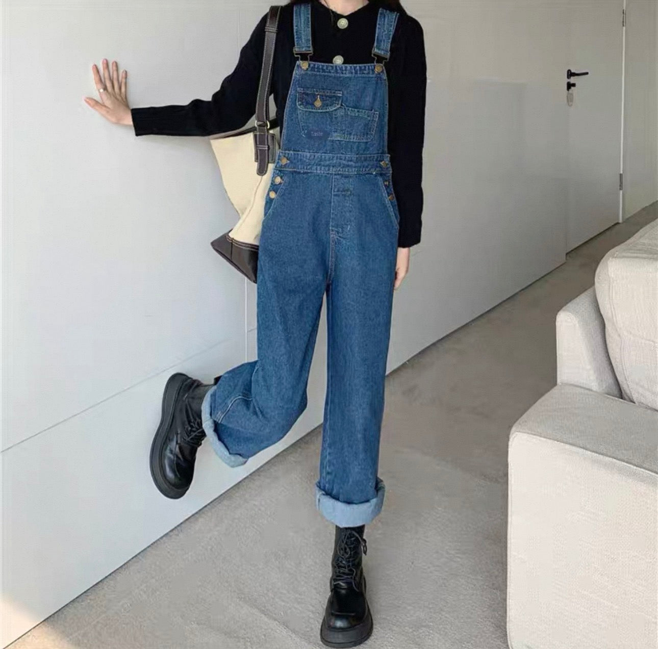 Person wearing blue denim overalls in a minimal indoor setting