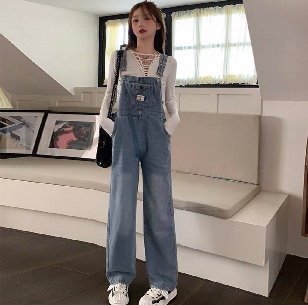 Person wearing a denim overalls outfit in a modern living room.