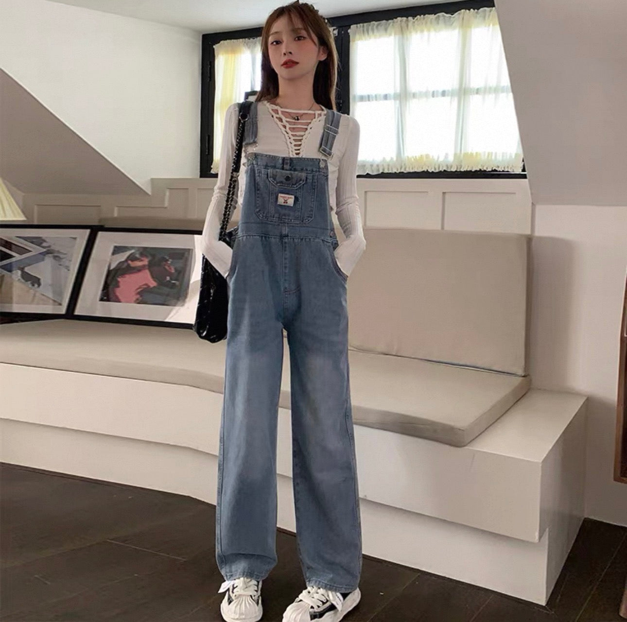 Person wearing a denim overalls outfit in a modern living room.