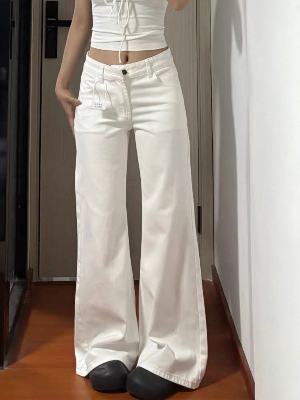 Person wearing white wide-leg jeans indoors.