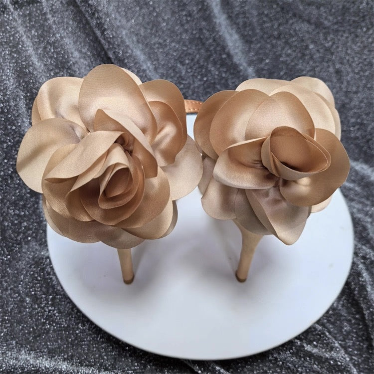 Nude satin stiletto heels with large floral embellishments on the back.