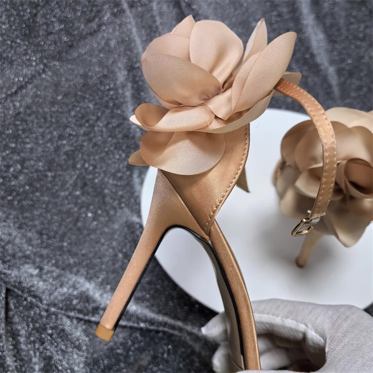 Nude satin stiletto sandal with large floral embellishment and ankle strap.