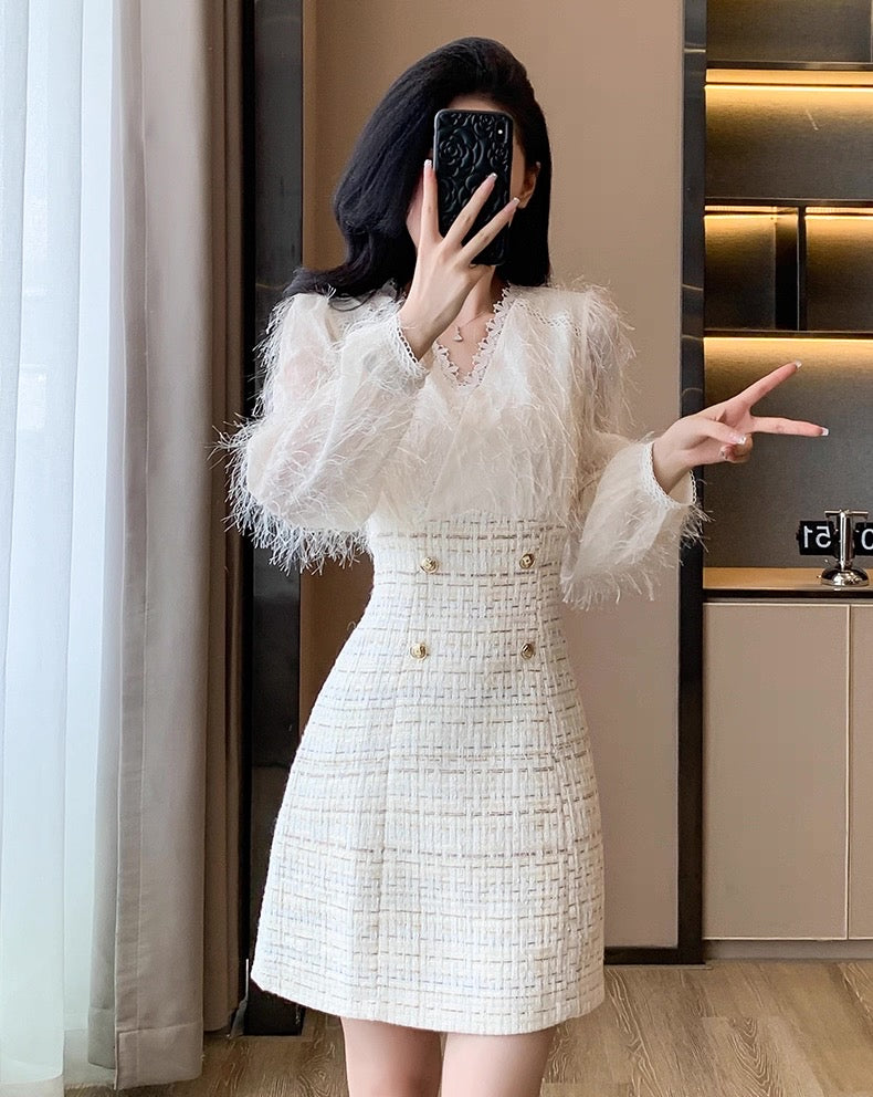 Person wearing a white dress with feather details in an indoor setting.