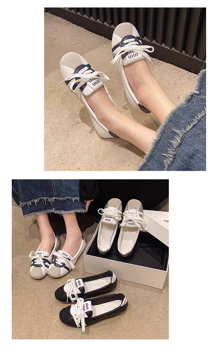 White shoes with black accents worn by a person on a beige carpet.