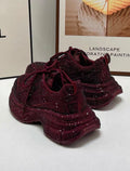 Burgundy glittery sneakers on a white surface with a blurred background