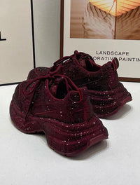 Burgundy glittery sneakers on a white surface with a blurred background