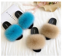 Pair of slippers with blue and beige fur on a white surface.