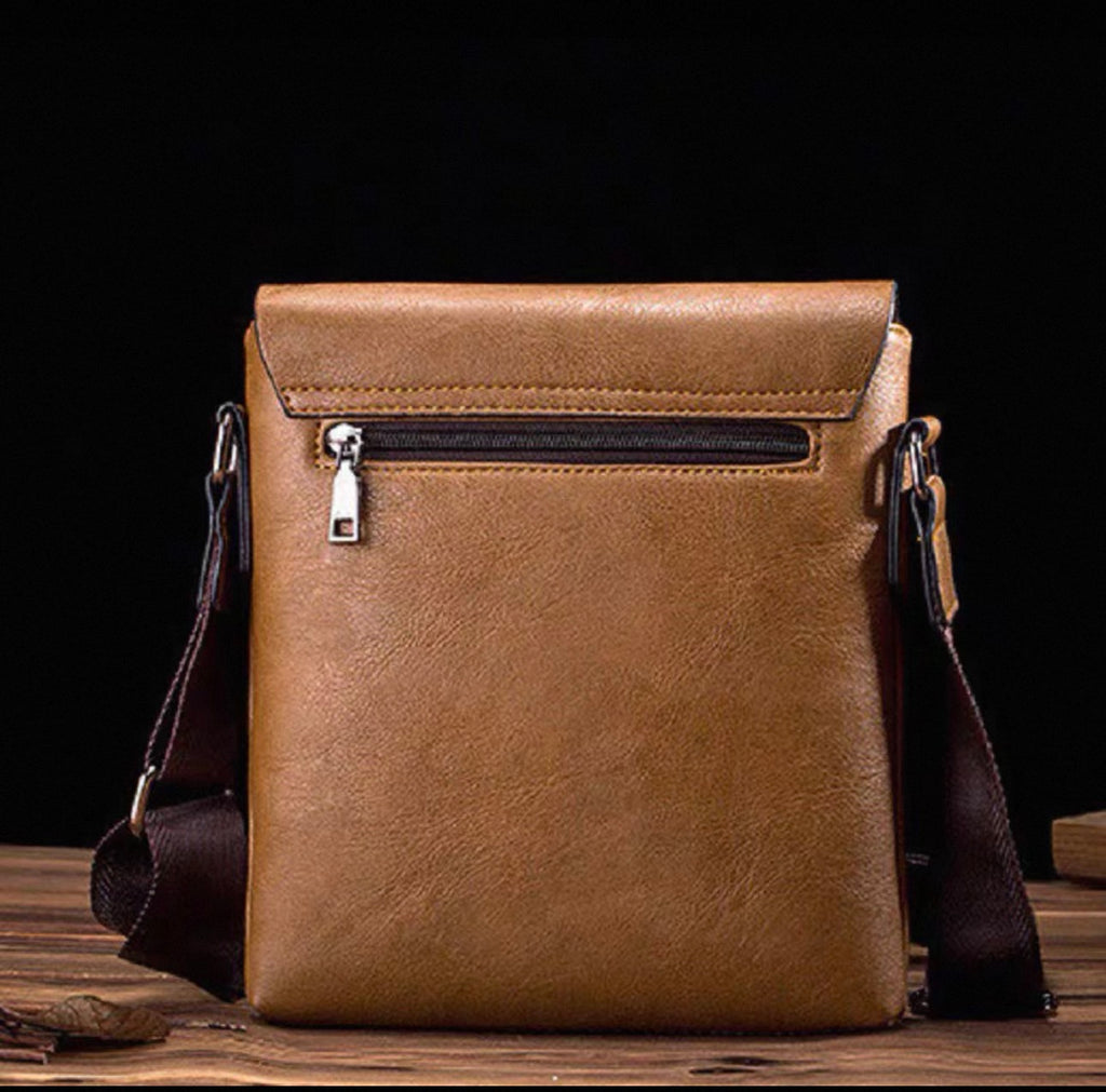 Brown leather crossbody bag on a wooden surface with a dark background